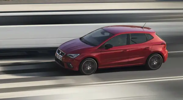 Coche rojo deportivo en movimiento, rápido como caballos salvajes en la carretera.
