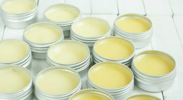 Piccoli barattoli argentati pieni di balsamo giallo, un prodotto naturale a base di cera d'api, pronti per essere usati.