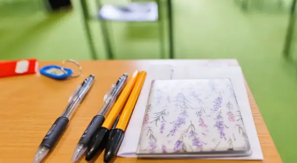 Długopisy i notes z lawendą na drewnianym biurku.