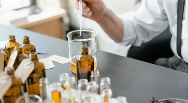 Ricerca su coumarin cos'è: un profumiere testa essenze in ambrate bottigliette, con un contagocce in un becher.