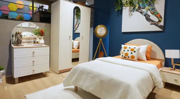 Ein gemütliches boho style jugendzimmer mit weißem Bett, Kleiderschrank und Kommode. Ein buntes Chamäleon-Bild ziert die Wand.