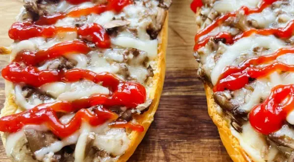 Zapiekanki z pieczarkami i serem na chrupiącej bagietce, polane ketchupem.