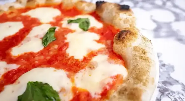 Pyszna pizza margherita z rozpływającym się serem mozzarella, sosem pomidorowym i świeżą bazylią na chrupiącym cieście.