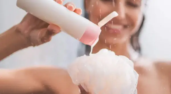 Mujer sonriente aplica shower cream para que sirve: limpieza e hidratación para una piel suave y radiante.