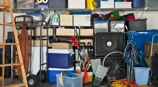 Organizzazione garage con idee cantina fai da te: scatole, attrezzi, slitta, ruote, casse audio e contenitori blu.