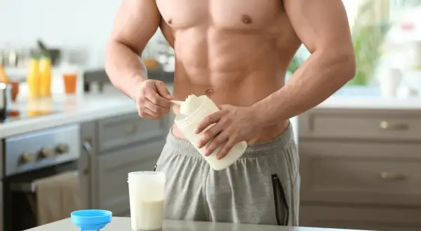 Muskulöser Mann bereitet Proteinshake zu. Informiere dich über mögliche proteinpulver nebenwirkungen, bevor du es verwendest.