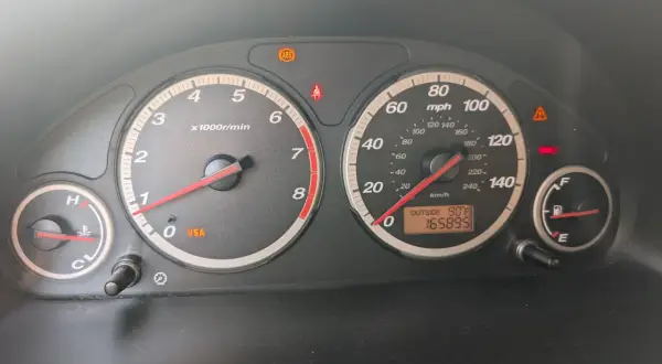 Kontrolki na desce rozdzielczej Hondy CR-V: świeci się kontrolka VSA, ABS, hamulców. Temperatura zewnętrzna 90°F, przebieg 165895.