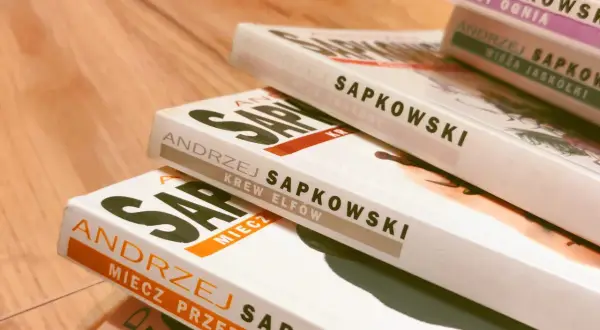 Pięć książek Andrzeja Sapkowskiego ułożonych na drewnianym blacie. Widoczne tytuły: "Chrzest ognia", "Wieża Jaskółki", "Czas pogardy", "Krew elfów", "Miecz przeznaczenia".