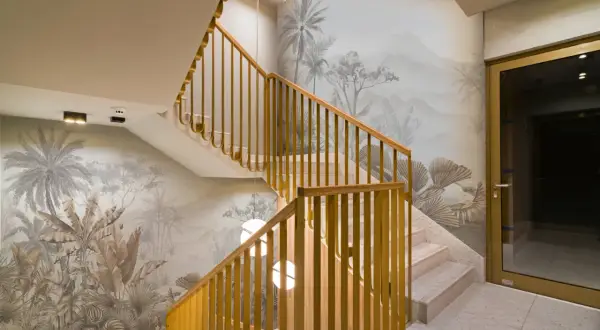 Habillage mur cage d'escalier avec un décor tropical en camaïeu. Escalier en marbre et rambarde en bois doré.