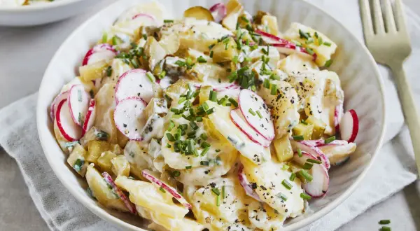 Kartoffelsalat mit Joghurt, Radieschen und Schnittlauch, garniert mit Pfeffer. Ein leichter und frischer Genuss.
