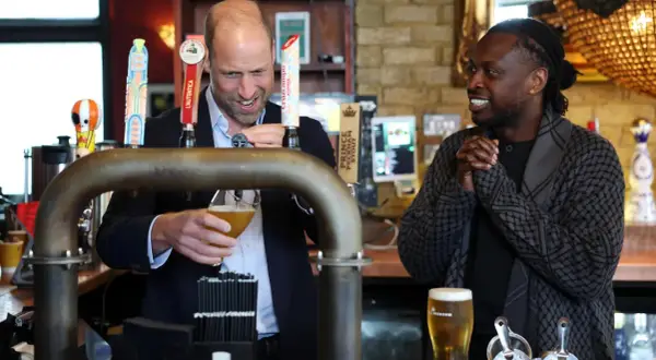 Uomo che versa una pinta di birra, mentre un altro uomo sorride.