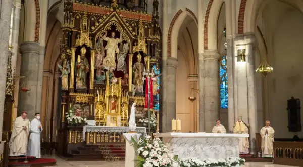W kościele trwa msza. 1 maja święto kościelne, kapłani w szatach liturgicznych przy ołtarzu.