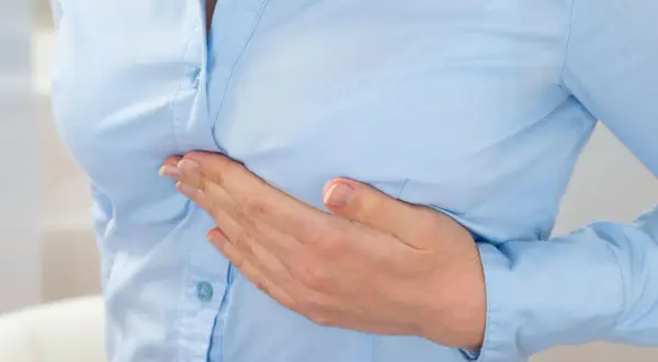 Dłoń na piersi, symbol bólu lub niepokoju związanego z rakiem zapalnym piersi.