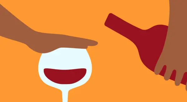 En hand stoppar ett vinglas med rött vin, medan en flaska hälls. Känslan av ångest av alkohol kan vara överväldigande.