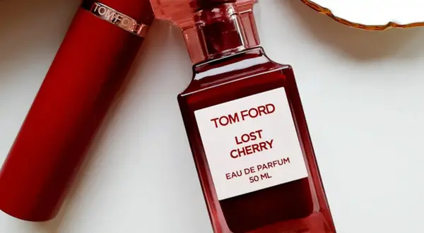 Elegancka butelka perfum Tom Ford Lost Cherry 50 ml w odcieniu głębokiej czerwieni, obok czerwonego opakowania.