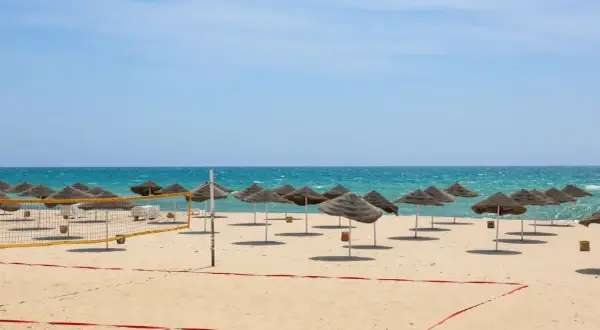 Piękna plaża w Tunezji we wrześniu. Słoneczna pogoda, turkusowe morze i rzędy parasoli zapraszają do relaksu.