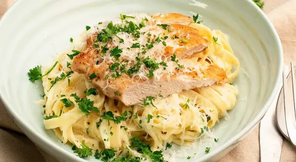 En krämig pasta alfredo kyckling, toppad med färsk persilja och riven parmesan. En utsökt måltid!
