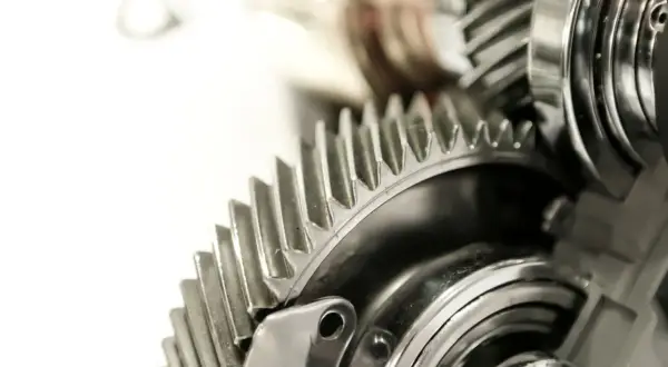 Metalowe koła zębate, część skomplikowanej przekładni ciernej, lśnią w zbliżeniu.