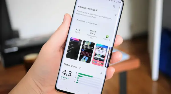Main tenant un smartphone Samsung, affichant la page d'une application sur le Play Store, prêt à mettre à jour une application.