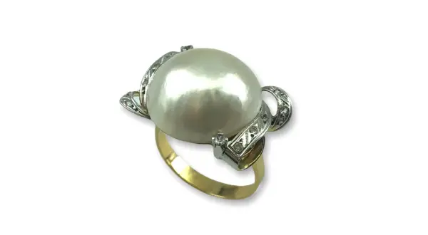 Anillo de oro con un gran anillo perla japonesa central, rodeado de pequeños diamantes incrustados en filigrana de plata.