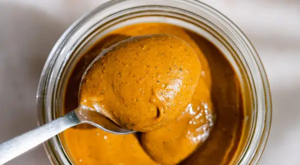 Une cuillère déborde de beurre de pistache onctueux, prêt à être dégusté. Une recette maison facile à réaliser.