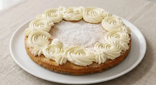 En härlig semmelkladdkaka glutenfri med fluffig grädde runt kanten, pudrad med florsocker.