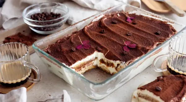 En härlig tiramisu i glasform, pudrad med kakao och dekorerad med kaffebönor och blommor. Perfekt för tips på bakning!