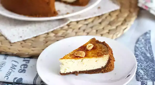 Tranche de cheesecake ricotta onctueux, garnie de noisettes caramélisées. Un délice gourmand.