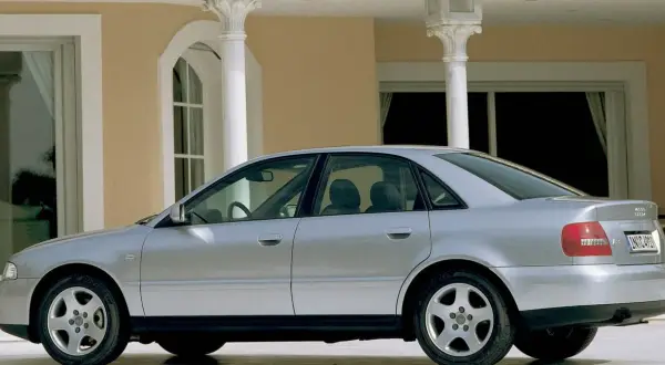 Srebrne Audi A4 B5, sedan, stoi przed budynkiem z kolumnami.