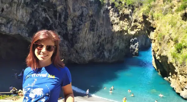 Giovane donna sorride in una baia con acqua turchese, uno dei tanti posti da visitare in Calabria.