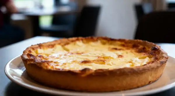 Une tarte au fromage dorée et appétissante, prête à être dégustée dans une ambiance chaleureuse.