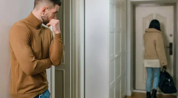 Mężczyzna zamyślony, gdy kobieta odchodzi. Widać, że facetowi nie zależy na kobiecie, bo nawet nie patrzy, jak wychodzi.