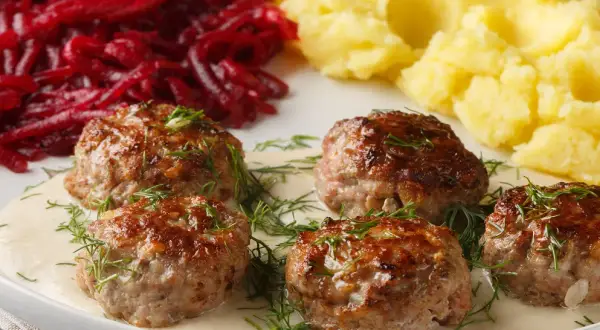 Soczyste klopsy w sosie z koperkiem, podane z purée ziemniaczanym i buraczkami.