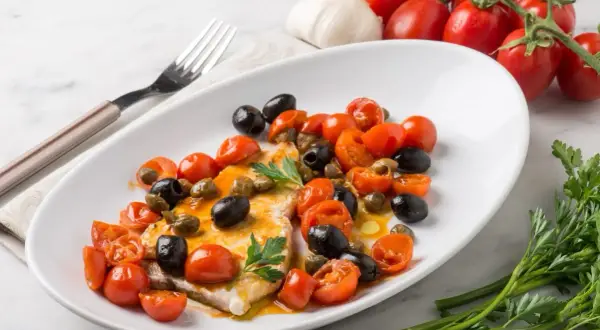 Piatto di pesce spada con pomodorini, olive nere e capperi. Una ricetta mediterranea gustosa e colorata.