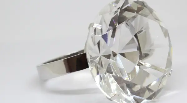 Duży, fasetowany kryształ w kształcie diamentu na srebrnym pierścionku.