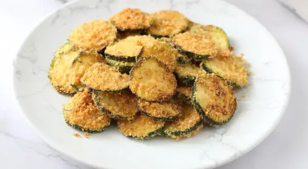 Fette di zucchine croccanti impanate, cotte nella friggitrice ad aria. Un contorno leggero e gustoso.