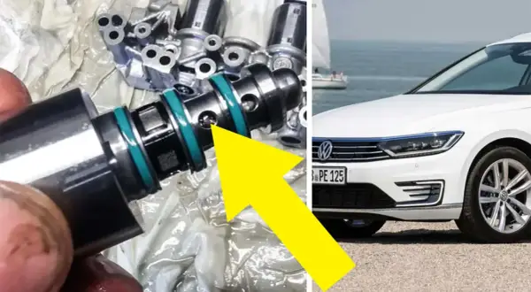 En mekaniker undersöker en del från en dubbeltrapp koppling, troligen relaterad till en vit Volkswagen vid havet.