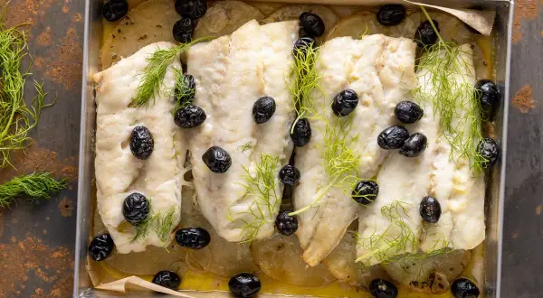 Merluzzo al forno con patate, olive nere e finocchietto fresco. Un piatto semplice e gustoso, pronto per essere servito.