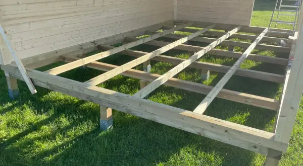 Holzkonstruktion für das **fundament gartenhaus** auf grünem Rasen, bereit für den Aufbau.