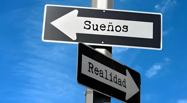 Señales de tráfico apuntan en direcciones opuestas: una hacia "Sueños" y otra hacia "Realidad". Frases de sueños y realidad.
