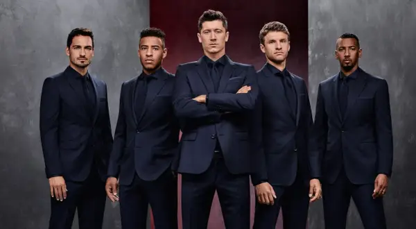 Pięciu mężczyzn w granatowych garniturach, prezentujących elegancję marki Hugo Boss.
