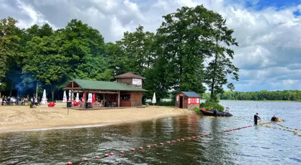 Plaża nad jeziorem w Szczecinku z barem i ratownikami przygotowującymi boje.