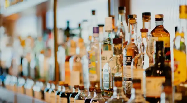 Rząd butelek z alkoholami, niektóre z etykietami wskazującymi, ile likier ma procent.