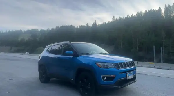 Blå Jeep Compass står vid vägkanten med en skog i bakgrunden. Kanske ett oväntat stopp, en Jeep Compass problem?
