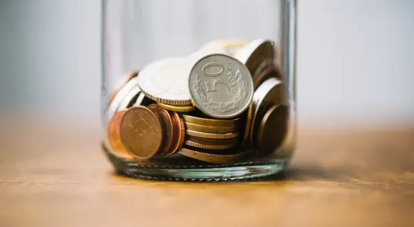 Słoik z monetami, w tym jedna z napisem "50 Groszy".