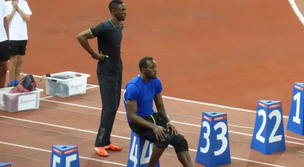 Usain Bolt, siedzący i stojący na bieżni, przypomina o jego rekordowej prędkości, która osiągnęła ponad 44 km/h.