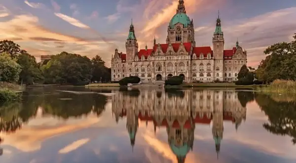 Nowy Ratusz w Hanowerze, jeden z najpiękniejszych zamków w Niemczech, odbija się w spokojnej tafli jeziora o zachodzie słońca.