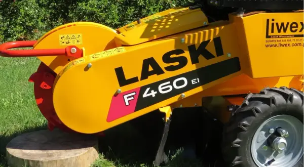 Żółty frez do pni drzew LASER F460 EI z czerwonym uchwytem i tarczą tnącą, gotowy do pracy na trawie.