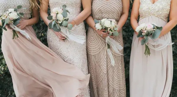 Brautjungfern in eleganten Kleidern mit Blumensträußen, perfekt für einen dresscode boho hochzeit.