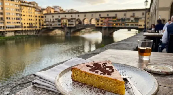 Ein Stück Schiacciata alla Fiorentina mit Kakaopulver-Dekor, serviert am Arno mit dem Ponte Vecchio im Hintergrund.